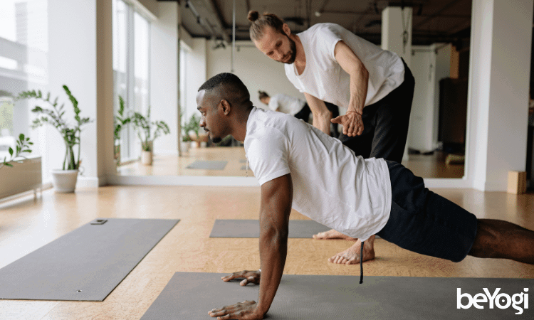 A yoga teacher practices what he learned in yoga teacher training with one of his students.