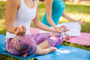 Closeup of a couple of women meditating and doing yoga at a park